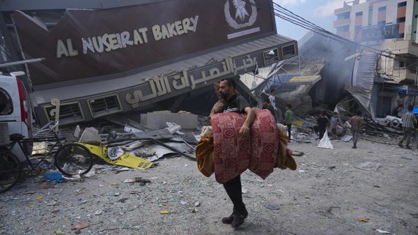 Palestinians walk past the Al Nuseirat Bakery, destroyed in an Israeli airstrike, in Nusseirat refugee camp Gaza Strip. - Sputnik International