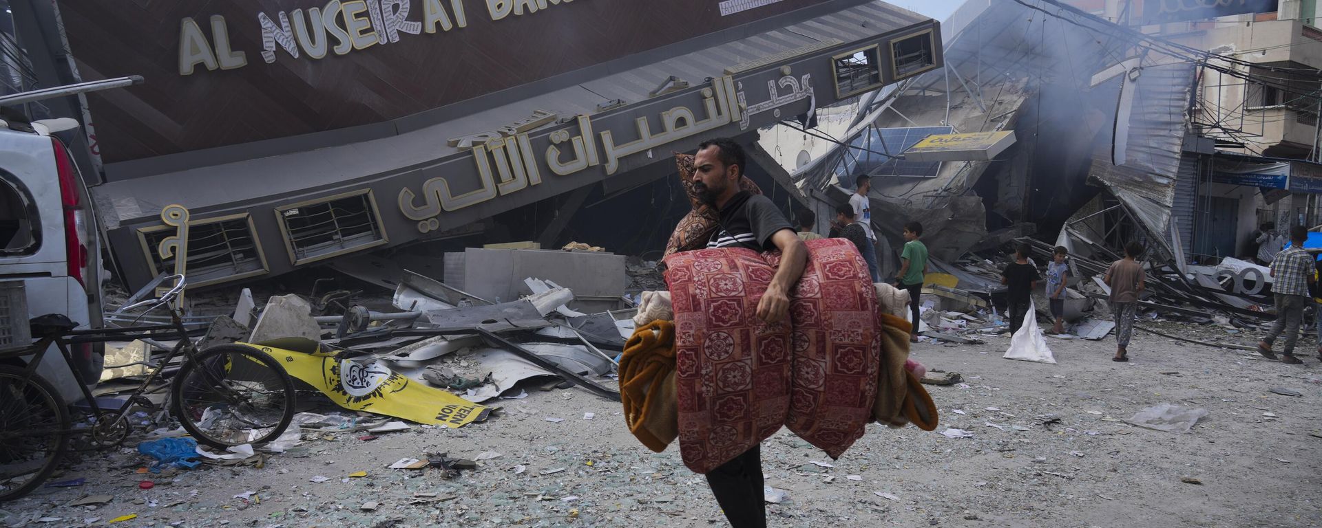 Palestinians walk past the Al Nuseirat Bakery, destroyed in an Israeli airstrike, in Nusseirat refugee camp Gaza Strip. Palestinians walk past the Al Nuseirat Bakery, destroyed in an Israeli airstrike, in Nusseirat refugee camp Gaza Strip. - Sputnik International, 1920, 19.10.2023
