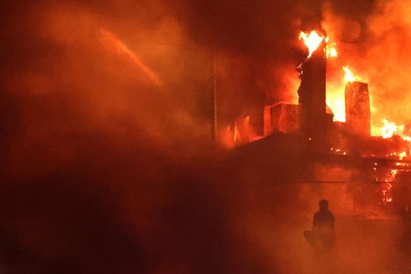 A Lebanese protester sits outside the US embassy as a fire rages behind its gates after clashes with Lebanese security forces on 18 October 2023, during a demonstration in solidarity with the people of Gaza in Awkar, East of Beirut, after a strike on a hospital in the Gaza Strip. - Sputnik International
