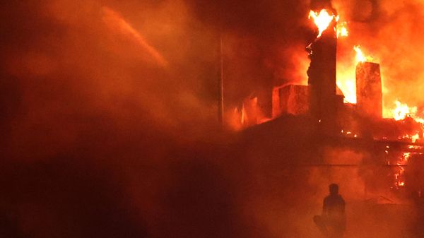 A Lebanese protester sits outside the US embassy as a fire rages behind its gates after clashes with Lebanese security forces on October 18, 2023, during a demonstration in solidarity with the people of Gaza in Awkar, East of Beirut, following a strike on a hospital in the Gaza Strip, killing at least 200 people on October 17, 2023 - Sputnik International