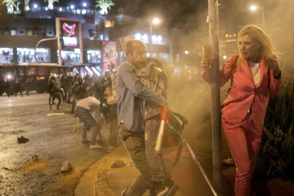 A man holds a boy as protesters run from tear gas launched by riot police during a rally in support of Palestinians, outside the Israeli Embassy in Athens. - Sputnik International