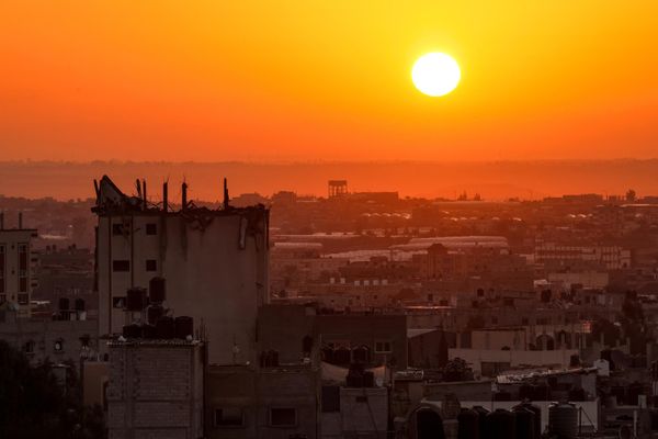 The sun rises behind a damaged building over the skyline of Khan Yunis in the southern Gaza Strip on October 19, 2023. - Sputnik International