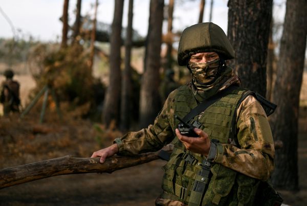 Trooper armed with radio poses against the background of a 2A36 Giantsint-B. - Sputnik International