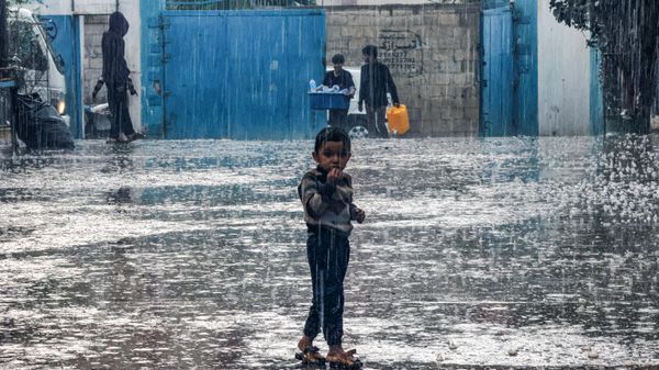 A boy stands in the rain at a school run by the United Nations Relief and Works Agency for Palestine Refugees in the Near East (UNRWA) in Rafah in the southern Gaza Strip on November 14, 2023. - Sputnik International