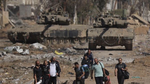 Palestinians fleeing the north along Salaheddine road help a man with a bandaged leg as they walk in front of Israeli army tanks in the Zeitoun district on the southern outskirts of Gaza City on November 24, 2023, following a four-day ceasefire that began early in the morning. Palestinians fleeing the north along Salaheddine road help a man with a bandaged leg as they walk in front of Israeli army tanks in the Zeitoun district on the southern outskirts of Gaza City on November 24, 2023, following a four-day ceasefire that began early in the morning. - Sputnik International