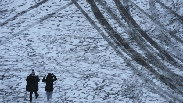 People walk through a parking lot after a winter storm dumped about 4 inches of snow on the area Saturday, Nov. 25, 2023, in Manhattan, Kan.  - Sputnik International