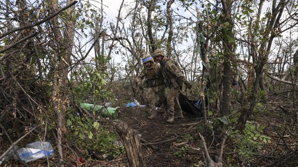 Ukrainian servicemen carry body bags with killed Ukrainian soldiers, through the trees at the frontline a few kilometers from Andreevka, September, 2023. - Sputnik International