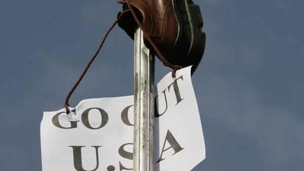 A shoe is raised during a protest against the US President's visit in the Shiite stronghold of Sadr City in Baghdad, Iraq, Monday. Dec. 15, 2008.  Iraqi journalist Muntadar al-Zeidi threw his shoes at President George W. Bush  during a press conference in Baghdad on Sunday, while yelling in Arabic. (AP Photo/Karim Kadim) - Sputnik International