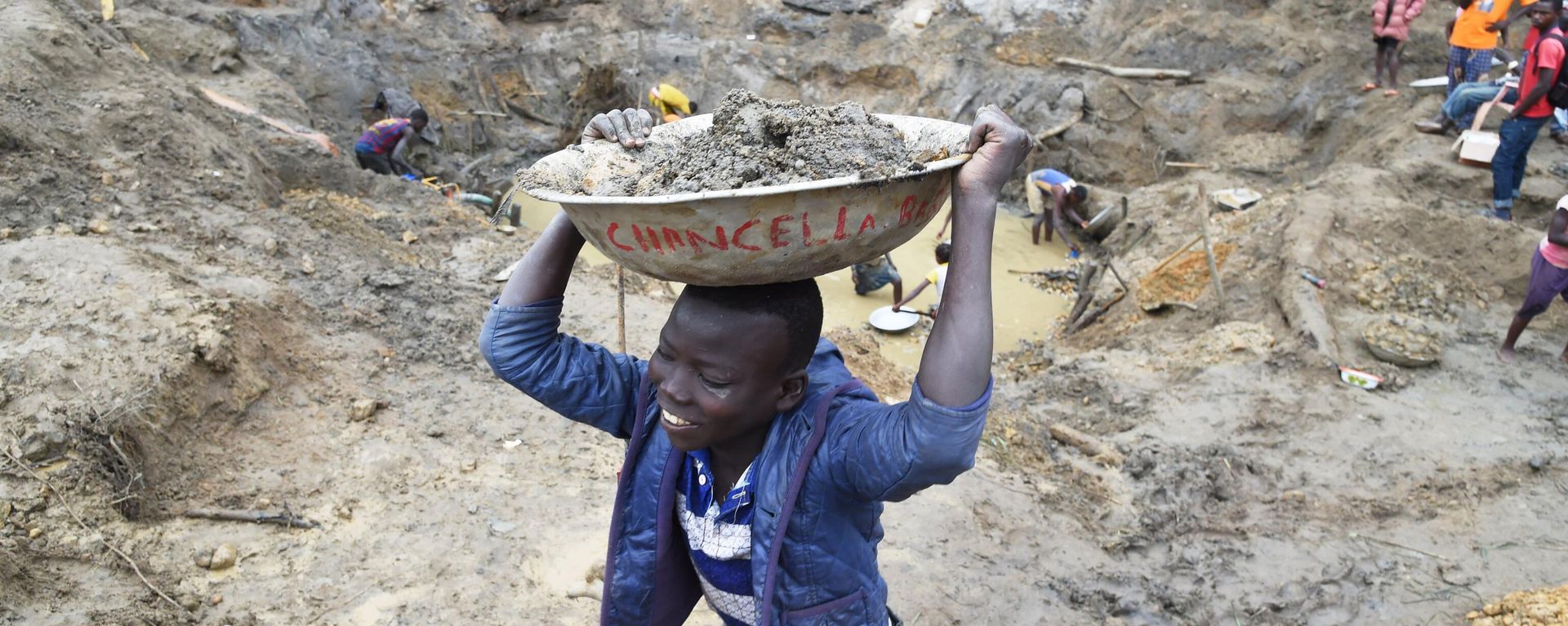 A child gold miner holds a bowl of earth on his head on May 5, 2014 while looking for gold in a traditional mine in the village of Gam, where gold mining in the main business activity of the region A child gold miner holds a bowl of earth on his head on May 5, 2014 while looking for gold in a traditional mine in the village of Gam, where gold mining in the main business activity of the region - Sputnik International, 1920, 17.12.2023