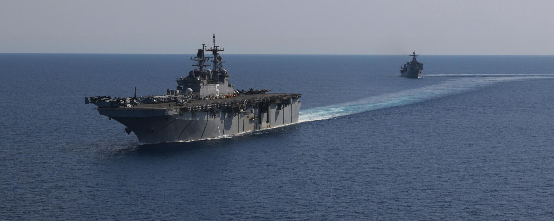 In this photo released by the U.S. Navy, the amphibious assault ship USS Bataan, front, and the landing ship USS Carter Hall, back travel through the Red Sea - Sputnik International, 1920, 22.12.2023