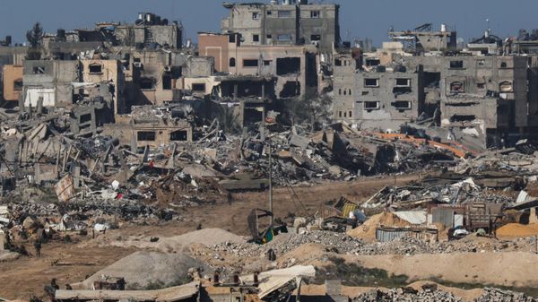 A picture taken from southern Israel bordering the Gaza Strip on December 22, 2023, shows an Israeli army tank rolling past debris of buildings in the Gaza Strip. - Sputnik International