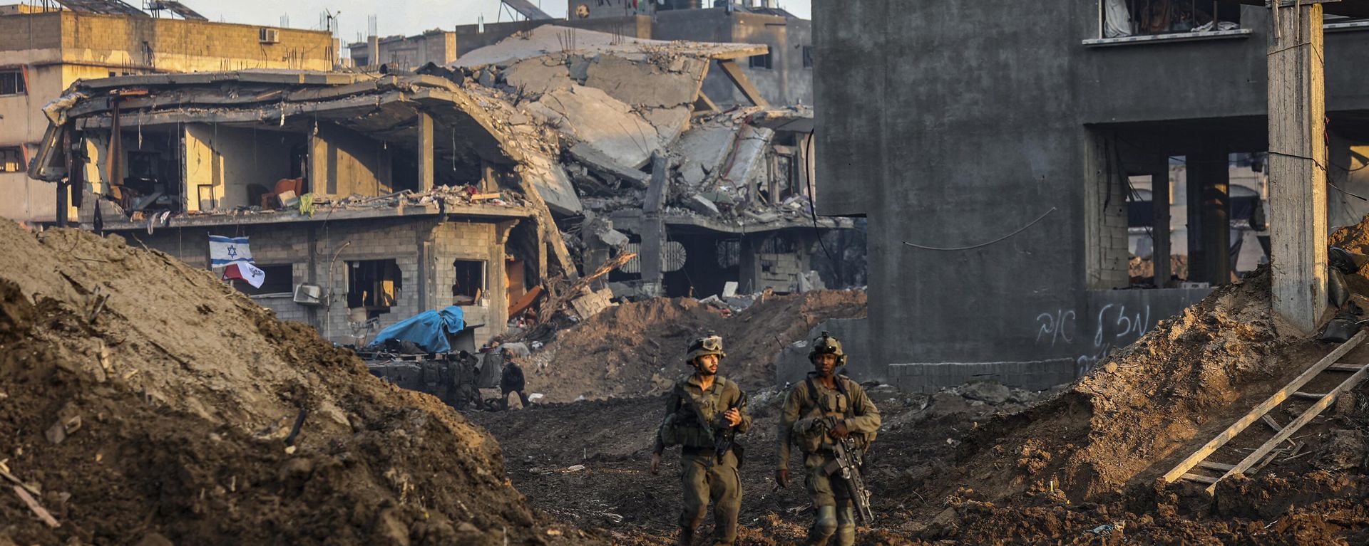This picture taken on December 19, 2023, shows Israeli soldiers walking past damaged buildings during a military operation in the north of the Gaza Strip. This picture taken on December 19, 2023, shows Israeli soldiers walking past damaged buildings during a military operation in the north of the Gaza Strip. - Sputnik International, 1920, 24.12.2023