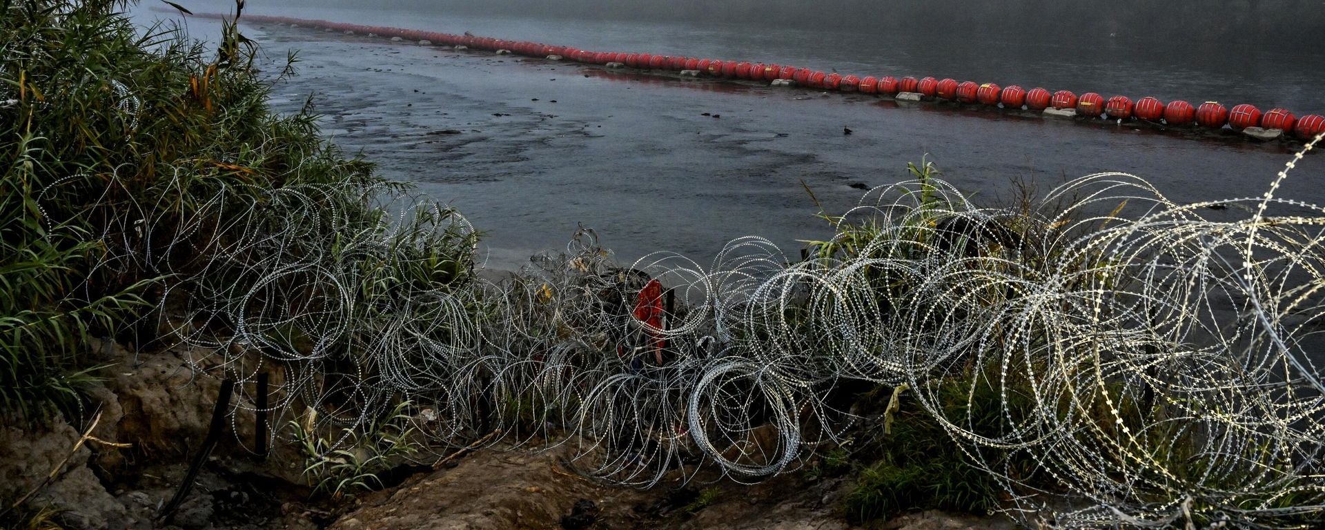 A floating barrier is deployed in the middle of the Rio Grande which forms the US-Mexico border at Eagle Pass, Texas, on December 23, 2023. Faced with the daily arrival of thousands of migrants from Mexico, US states and federal border police are declaring themselves overwhelmed, a crisis that is exposing the administration of US President Joe Biden to heavy fire from its Republican opponents. In recent weeks, the border police have reported some 10,000 people crossing the border every day, an even faster pace than in previous months. (Photo by CHANDAN KHANNA / AFP) - Sputnik International, 1920, 24.12.2023