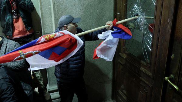 Protester attempts to smash the window of a door leading inside Belgrade's city council during violent demonstrations December 24, 2023 protesting the results of recent parliamentary elections. - Sputnik International
