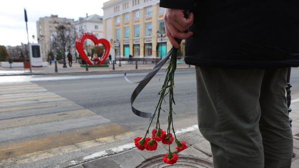Belgorod resident stands near makeshift memorial to civilians killed in Saturday's Ukrainian missile and MLRS attack on the southwestern Russian city of 340,000. December 31, 2023. - Sputnik International