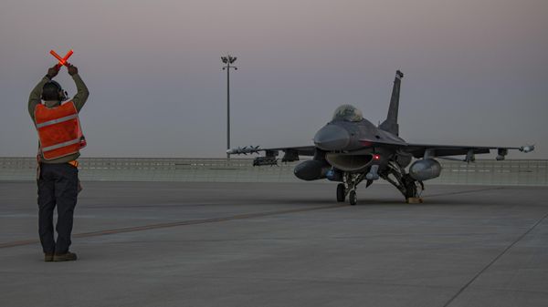 In this handout photo from the U.S. Air Force, an airman guides an F-16 Fighting Falcon during training at Al-Udeid Air Base, Qatar, Jan. 24, 2022.  - Sputnik International