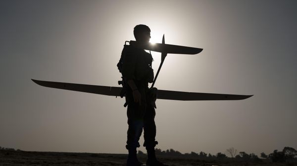 An Israeli troop stands against the silhouette of the Sun as he prepares a small spy drone for launch near Gaza. January 9, 2024. - Sputnik International