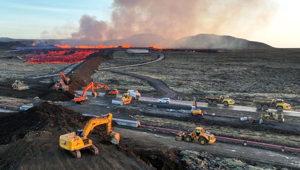 Aerial view shows emergency personnel using diggers to build a protective wall trying to prevent flowing lava to reach the center of the southwestern Icelandic town of Grindavik after eruption. - Sputnik International