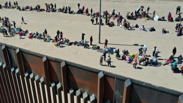 An aerial image shows migrants waiting along the border wall to surrender to Border Patrol agents for immigration and asylum claim processing after crossing the Rio Grande river into the US on the US-Mexico border in El Paso, Texas on May 11, 2023 - Sputnik International