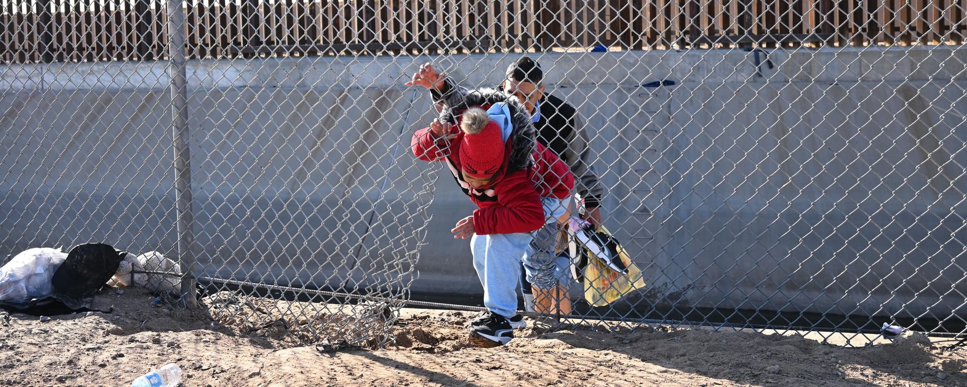 A family of migrants from Columbia climbs up through a canal fence after crossing under a hole in the US-Mexico border wall in El Paso, Texas, on December 19, 2022 - Sputnik International, 1920, 27.01.2024