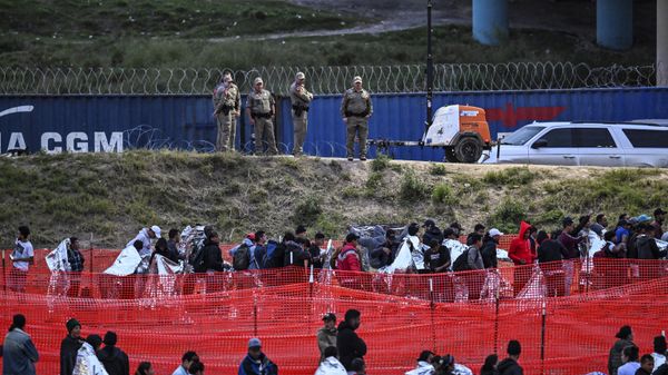 Customs and Border Protection agents stand guard as immigrants wait to be processed at a US Border Patrol transit center after crossing the border from Mexico at Eagle Pass, Texas, on December 22, 2023. - Sputnik International