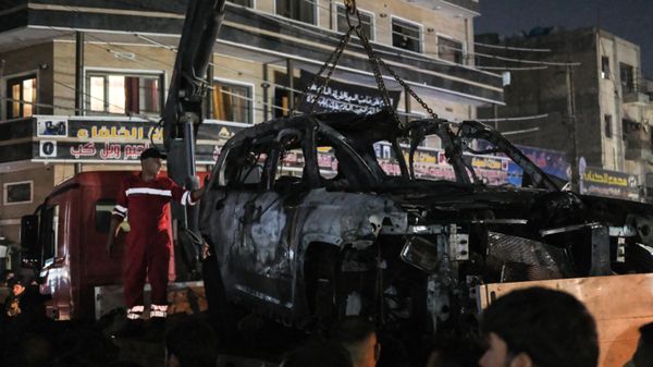 People watch as a vehicle that was hit by a drone strike, reportedly killing three people including two leaders of the Kataib Hezbollah militant group, is carried away in Baghdad on February 7, 2024 - Sputnik International