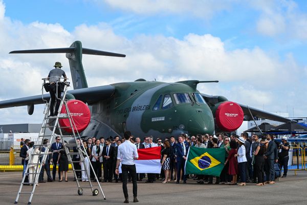 A group of people pose for photograph with flags of Singapore and Brazil in front of an Embraer C390 Millennium aircraft. - Sputnik International