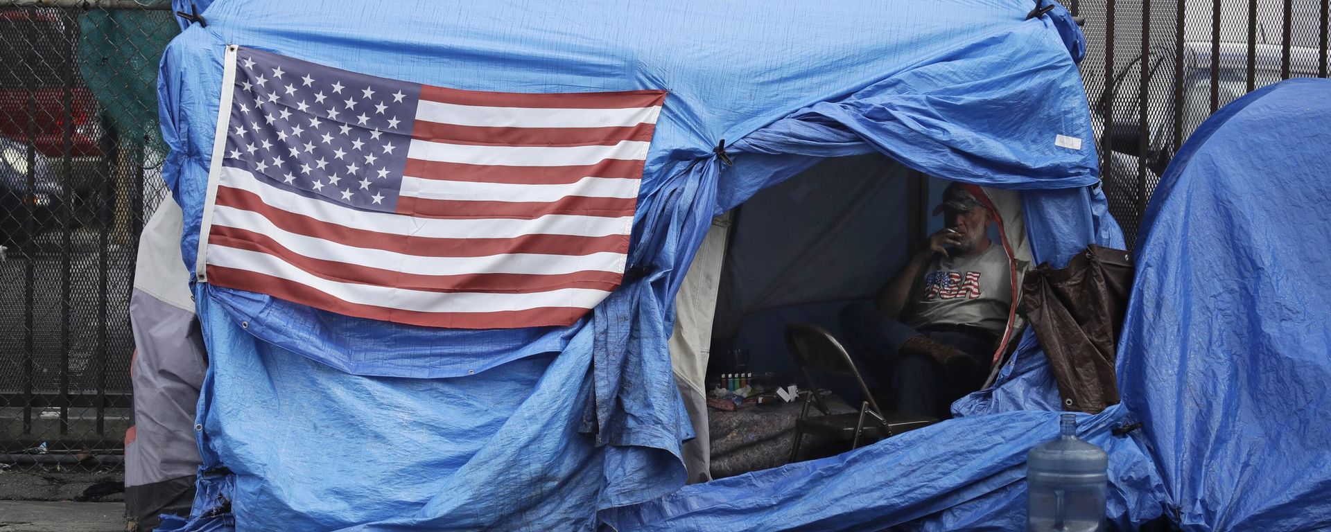 A man smokes inside a tent on skid row Friday, March 20, 2020, in Los Angeles. Auditors said Tuesday, Aug. 24, 2021 - Sputnik International, 1920, 09.07.2025