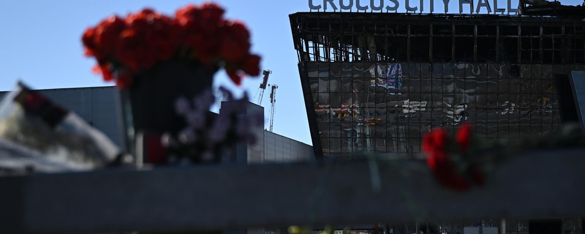 Flowers and toys are placed on the roadside in front of the burnt-out Crocus City Hall following a terrorist attack - Sputnik International, 1920, 08.04.2024