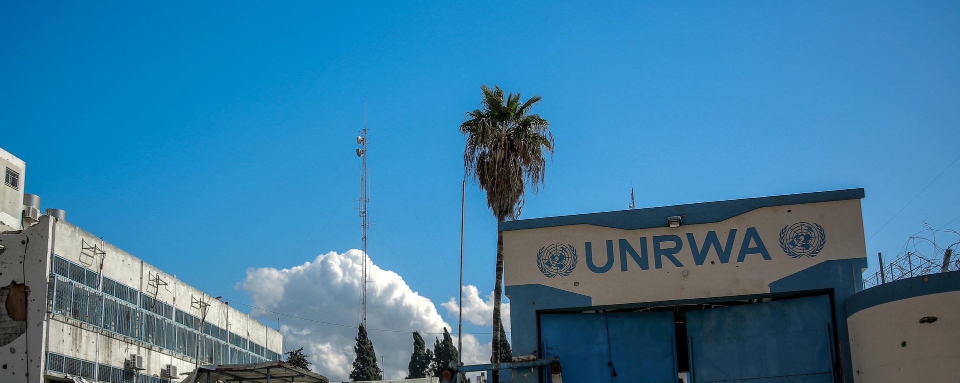 People walk past the damaged Gaza City headquarters of the United Nations Relief and Works Agency for Palestine Refugees (UNRWA) on February 15, 2024, amid ongoing battles between Israel and the militant group Hamas. - Sputnik International, 1920, 16.04.2024