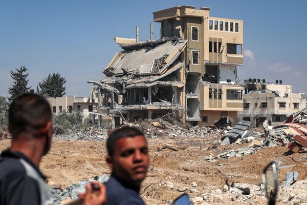 Men ride a motorcycle past an annihilated building. - Sputnik International