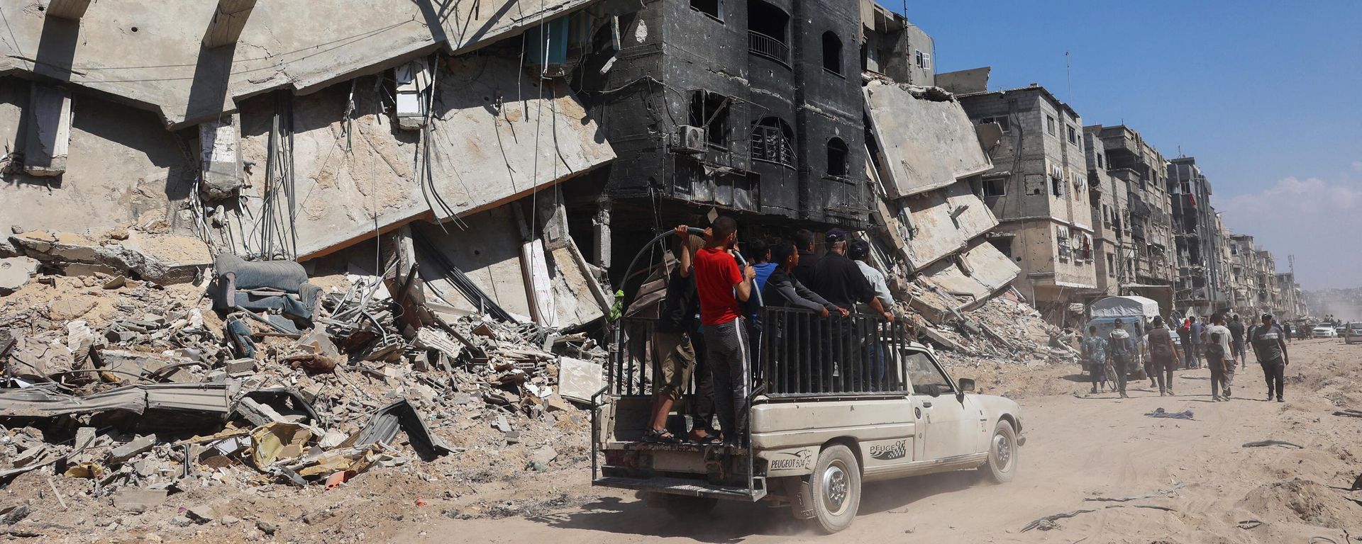 Palestinians use a road in front of damaged buildings in Khan Yunis - Sputnik International, 1920, 22.04.2024