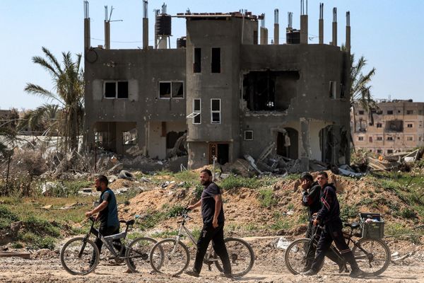 Men walk with bicycles along a heavily damaged road. - Sputnik International