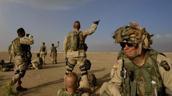 Soldiers from the 3rd Battalion of the 101 Airborne Brigade assembled on an airstrip wait for helicopters to pick them up for a mission, some waving to a passing Apache assault helicopter, at a base in northwestern Iraq, about 100 kilometers from the Syrian border, Sunday, May 18, 2003 - Sputnik International
