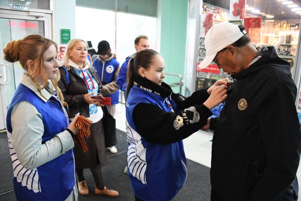 Activists of Russia's national Victory Volunteers movement help a passerby with a St. George Ribbon in a Vladivostok mall. - Sputnik International