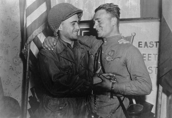 nd Lt. William Robertson and Lt. Alexander Sylvashko standing in front of a sign that reads East Meets West symbolizing the historic meeting of the Soviet and US Armies - Sputnik International