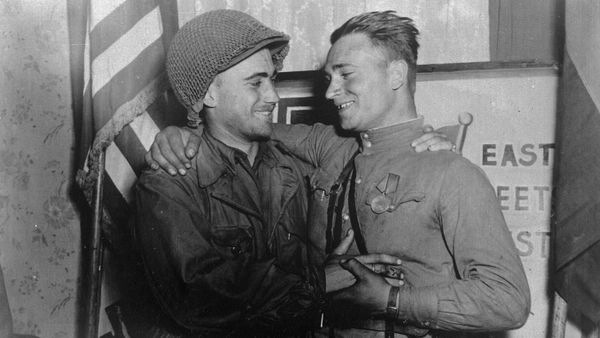 2nd Lt. William Robertson and Lt. Alexander Sylvashko standing in front of a sign that reads East Meets West symbolizing the historic meeting of the Soviet and US Armies - Sputnik International