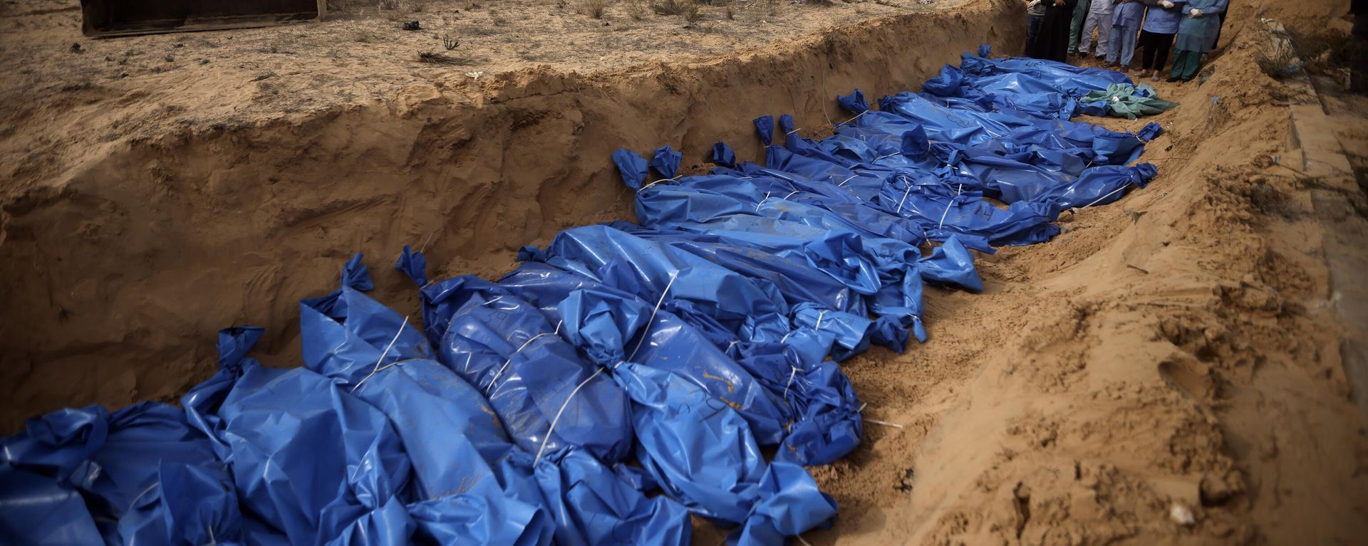 Palestinians pray over bodies of people killed in the Israeli bombardment who were brought from the Shifa hospital before burying them in a mass grave in the town of Khan Younis, southern Gaza Strip on Nov. 22, 2023 - Sputnik International, 1920, 28.04.2024