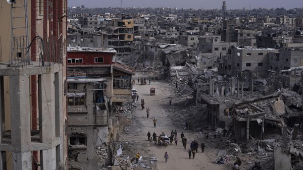 Palestinians walk through the destruction in the wake of an Israeli air and ground offensive in Khan Younis, southern Gaza Strip, Monday, April 8, 2024 - Sputnik International