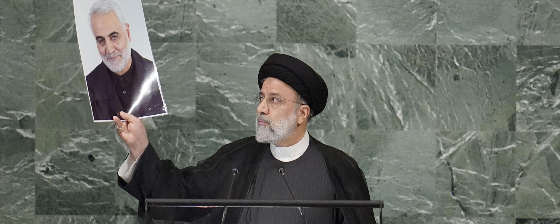 President of Iran Ebrahim Raisi holds up a photo of slain Iranian Gen. Qassem Soleimani, as he addresses the 77th session of the United Nations General Assembly - Sputnik International, 1920, 20.05.2024