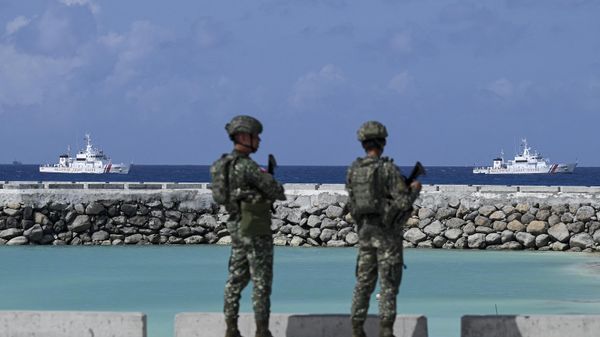 Philippine soldiers look at Philippine Coast Guard vessels near Thitu Island in the disputed South China Sea on December 1, 2023. - Sputnik International