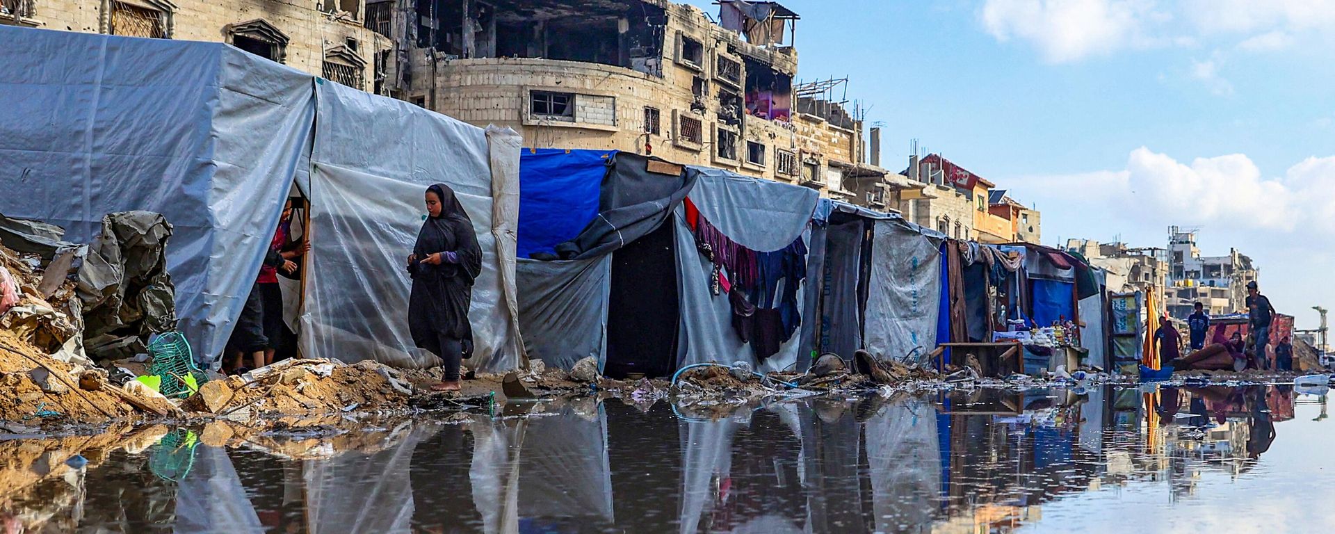 Palestinians circle a puddle in front of destroyed buildings and tents in Khan Younis, Palestine - Sputnik International, 1920, 10.06.2024