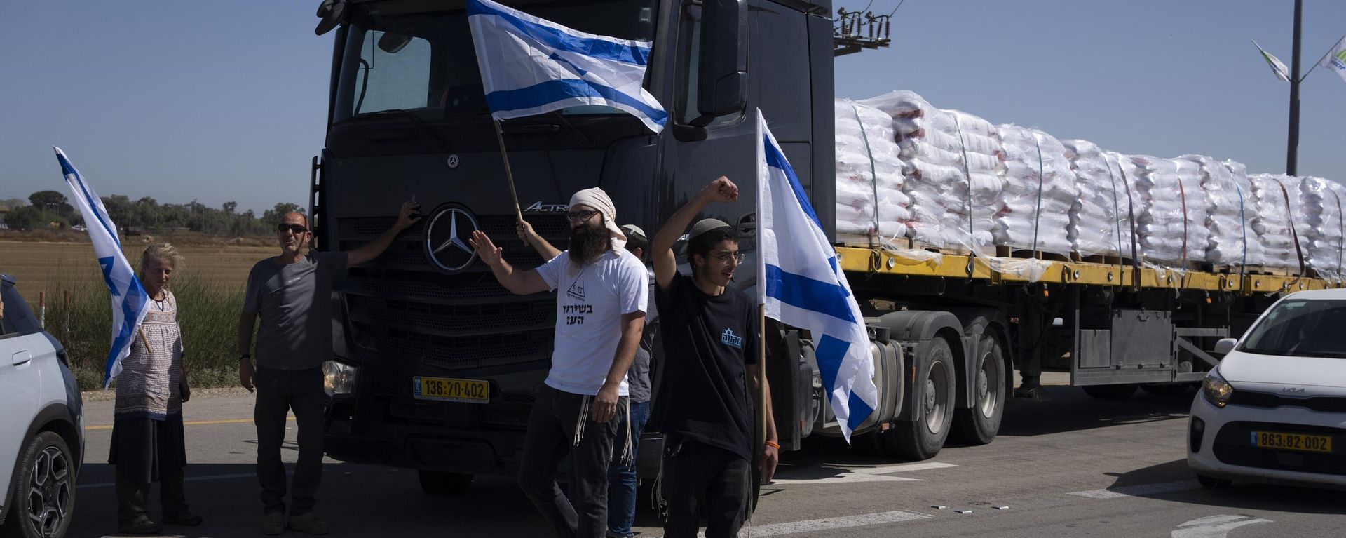 Holding Israeli flags people stand in front of trucks carrying humanitarian aid as they try to stop them from entering the Gaza Strip in an area near the Kerem Shalom border crossing in southern Israel, Thursday, May 9, 2024. (AP Photo/Leo Correa) Holding Israeli flags people stand in front of trucks carrying humanitarian aid as they try to stop them from entering the Gaza Strip in an area near the Kerem Shalom border crossing in southern Israel, Thursday, May 9, 2024. (AP Photo/Leo Correa) - Sputnik International, 1920, 27.05.2024