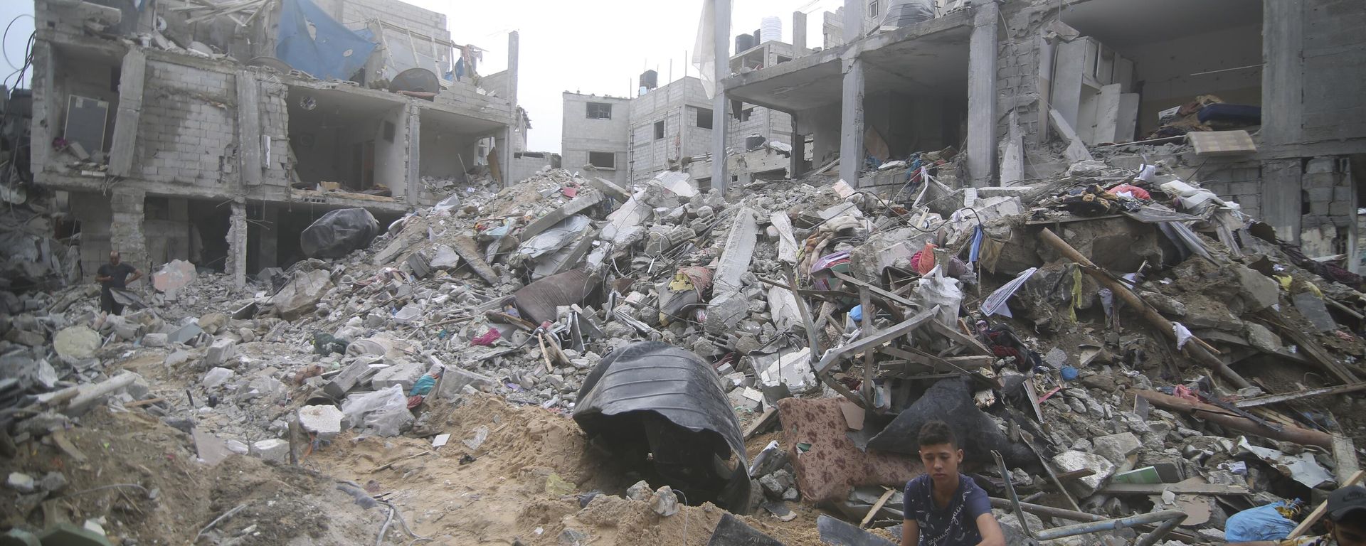 Palestinians sit by the rubble Abu Helal family in Rafah refugee camp, Gaza Strip, Monday, Oct. 9, 2023. The strike killed dozens of people - Sputnik International, 1920, 04.06.2024