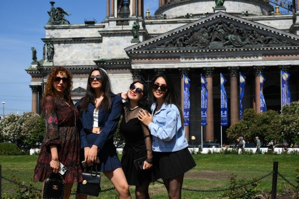 Women posing for a photo in front of the Saint Isaac's Cathedral that has been decorated with SPIEF-themed banners. - Sputnik International