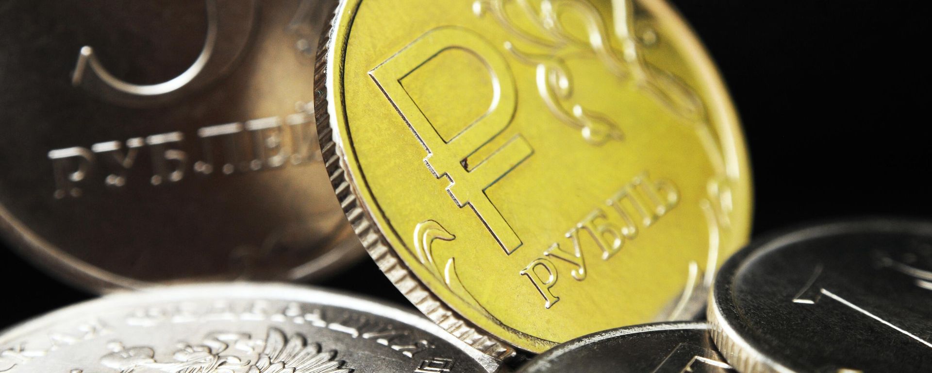 One ruble coin with the symbols of the Russian ruble. In the background is a Russian five-ruble coin - Sputnik International, 1920, 30.05.2026