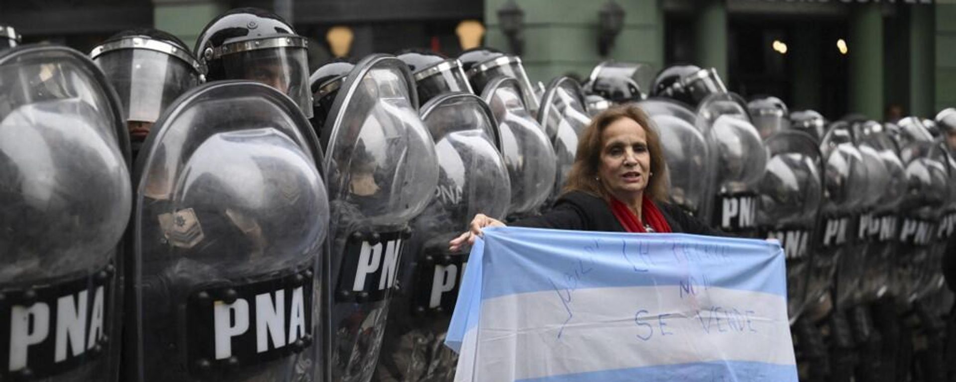 A woman holds Argentina's national flag in front of riot police during a protest in Buenos Aires on June 12, 2024. - Sputnik International, 1920, 13.06.2024