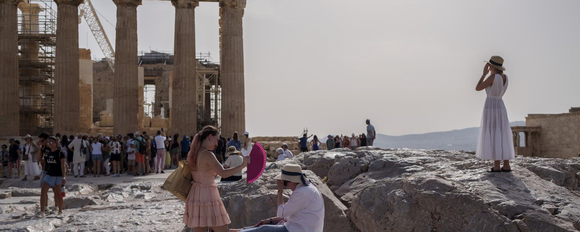 A tourist uses a hand fan to cool down another one sitting on a bench in front of the Parthenon at the ancient Acropolis, in Athens, Wednesday, June 12, 2024. The ancient site was closed to the public for five hours due to a heat wave that pushed temperatures to 39 degrees Celsius (102 Fahrenheit) in the capital and even higher in parts of central Greece. - Sputnik International, 1920, 14.06.2024