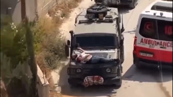 An injured Palestinian is driven through the streets of Jenin while strapped to an Israeli military vehicle, June 21, 2024 - Sputnik International