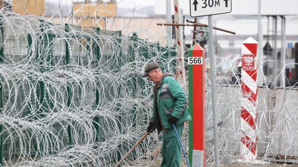 A man sweeps rubbish at the Bruzgi-Kuznica border crossing on the Belarusian-Polish border where a migrants' camp was located, in the Grodno region on November 19, 2021.  - Sputnik International